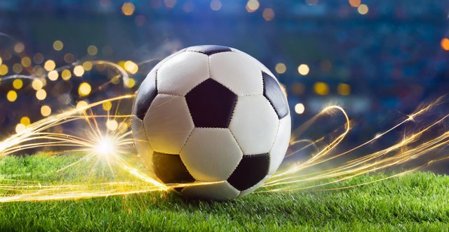 Fußball auf Rasen mit Lichtern im Hintergrund