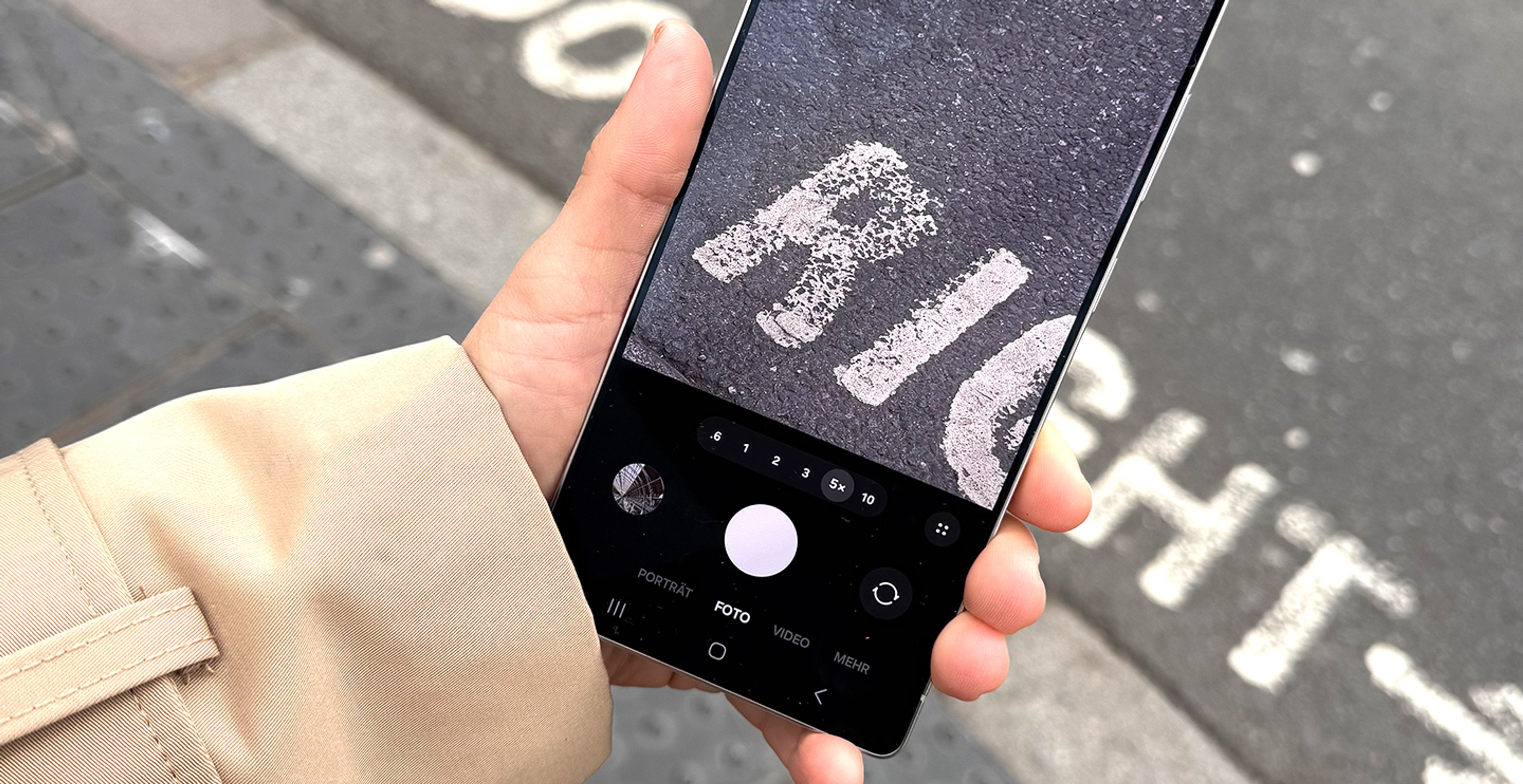 Eine Person fotografiert mit ihrer Handykamera eine Straße